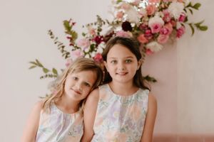 Romantic spring portrait with pink floral arrangements against soft pink background.