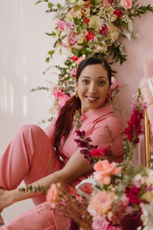 Portrait surrounded by pink and coral floral arrangements in romantic setting.