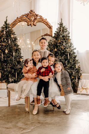 Family gathered for holiday photos in front of Christmas trees with ornate gold mirror and white decor.