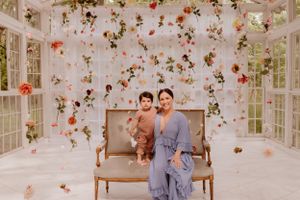 Elegant portrait in a conservatory setting with hanging floral arrangements and natural light.