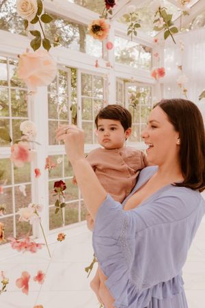 Joyful moment in a sunlit studio decorated with hanging flowers and roses.