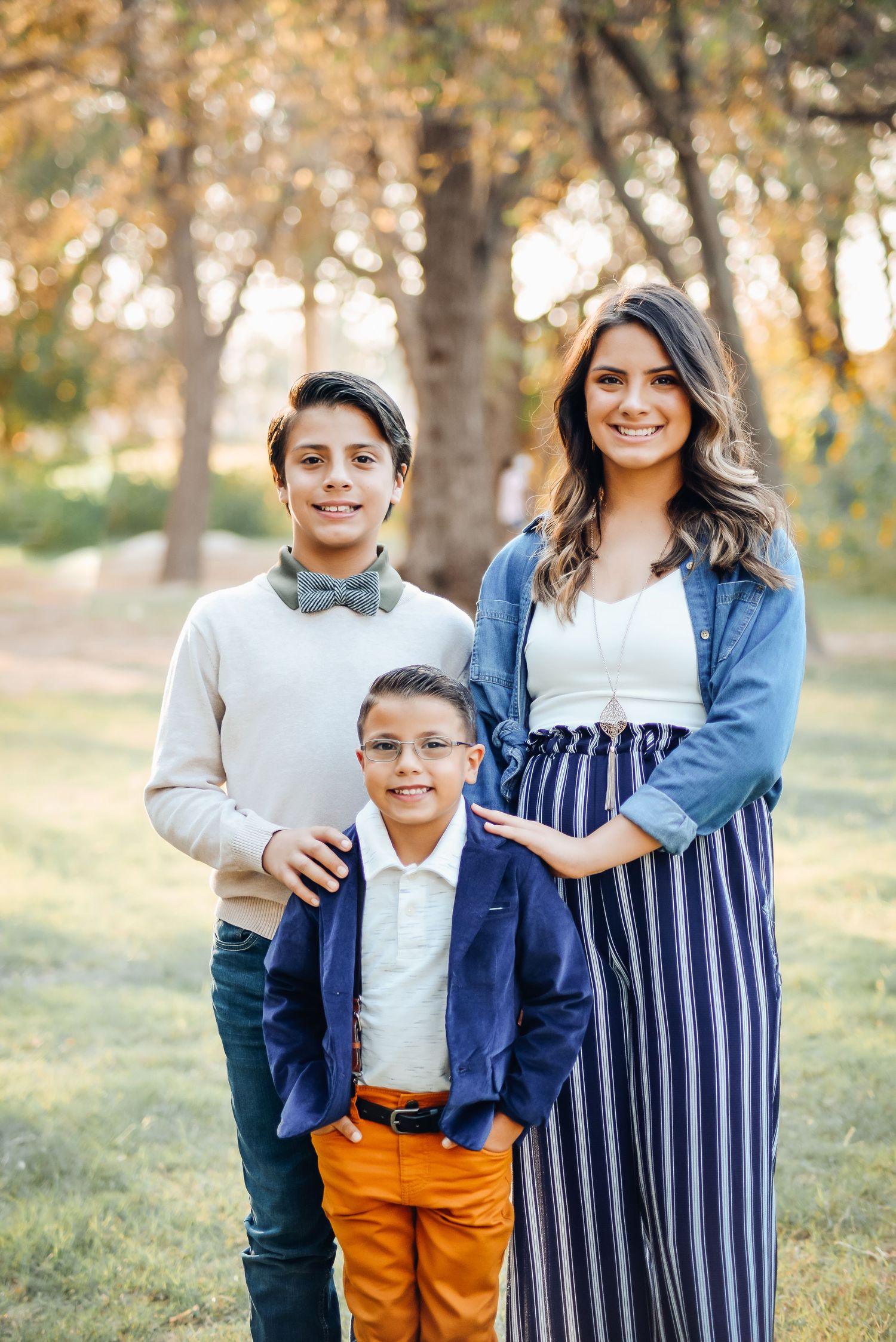 Family portrait session in coordinated blue and white outfits in a sunny outdoor setting.
