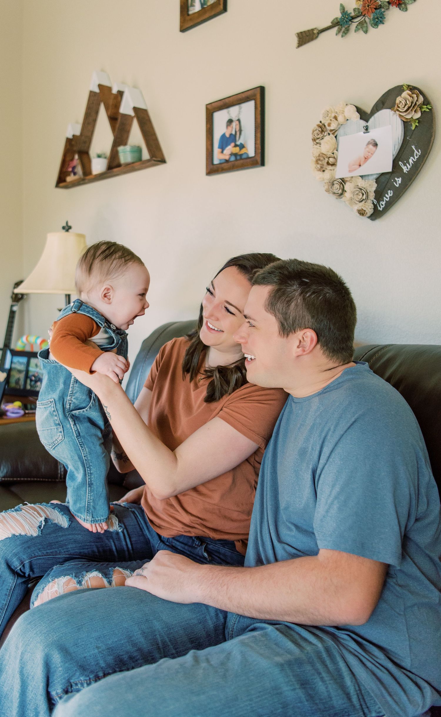 A family shares a joyful moment together while sitting on a gray couch in their living room decorated with wall art.