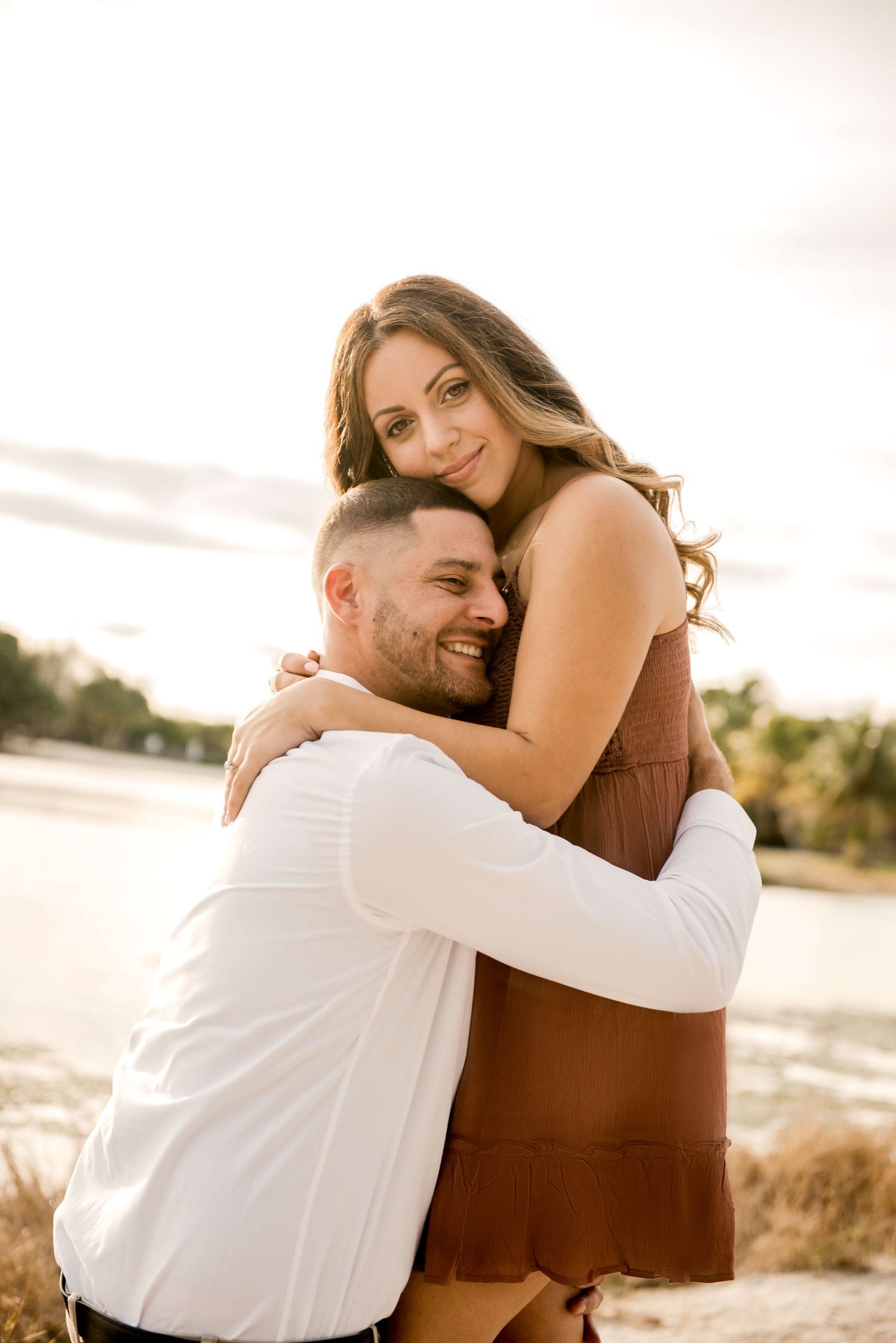 A joyful embrace captured during a sunset beach engagement session.