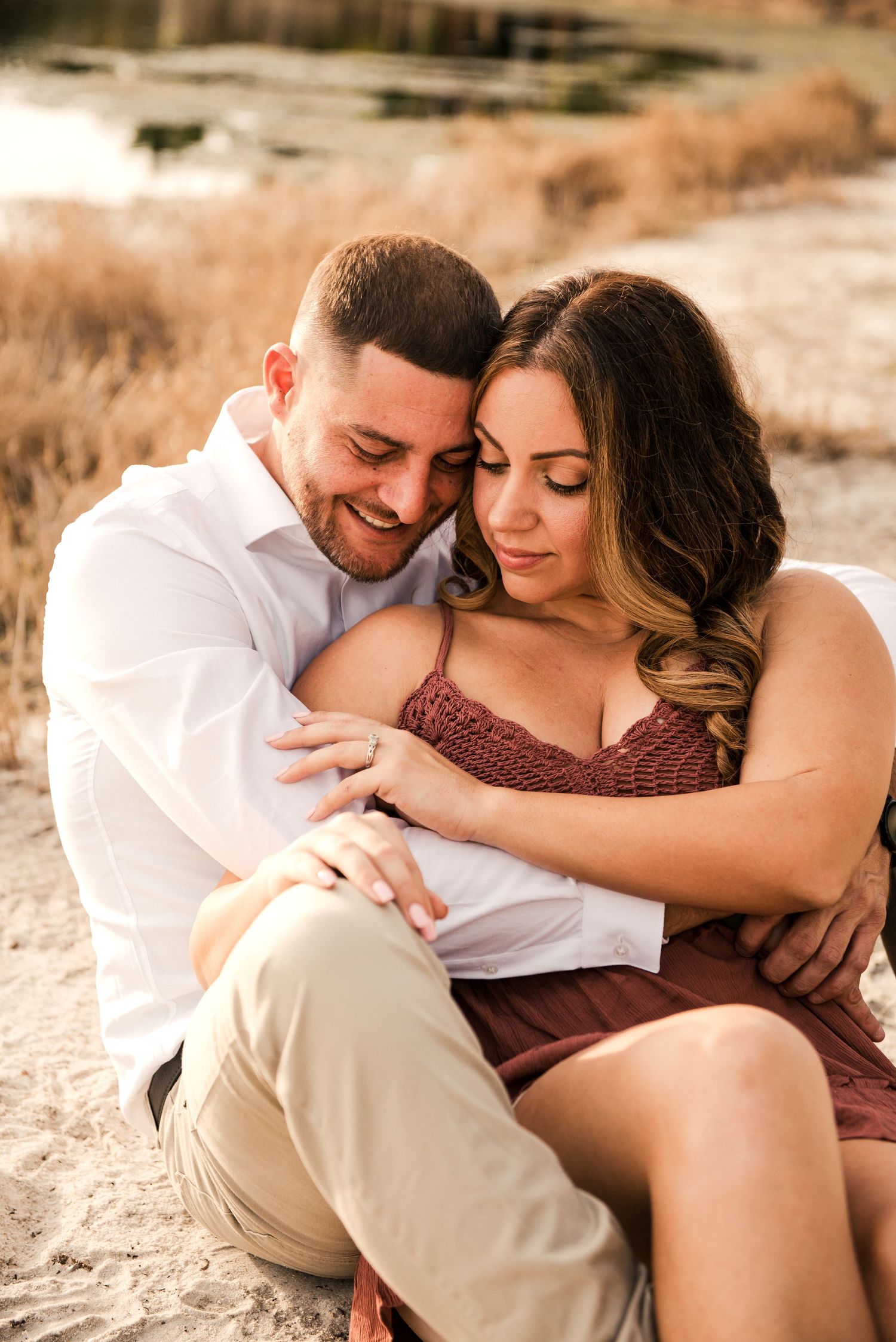 A romantic couple shares an intimate moment while sitting together outdoors during golden hour.