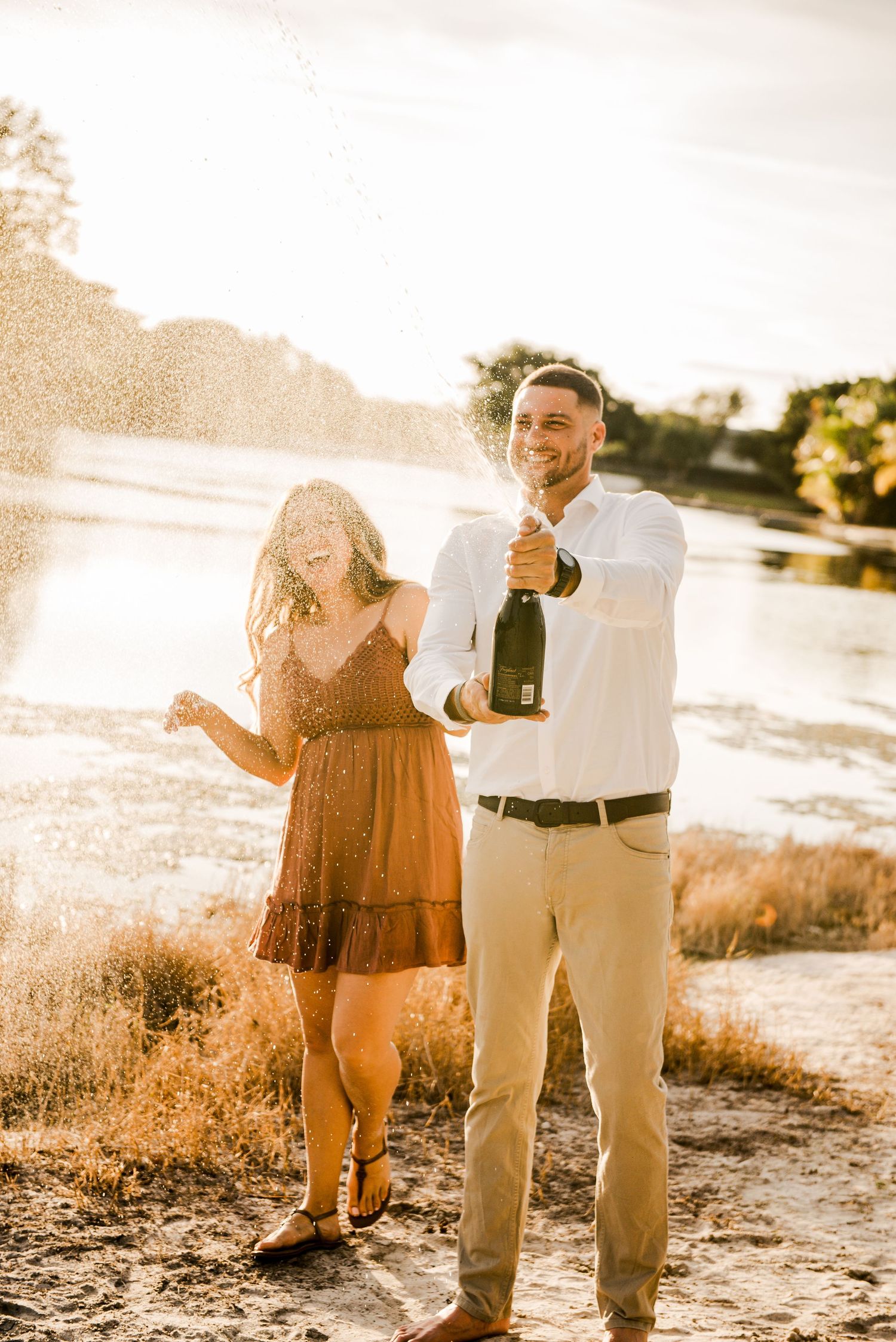 A celebratory moment with champagne during a beach engagement session.