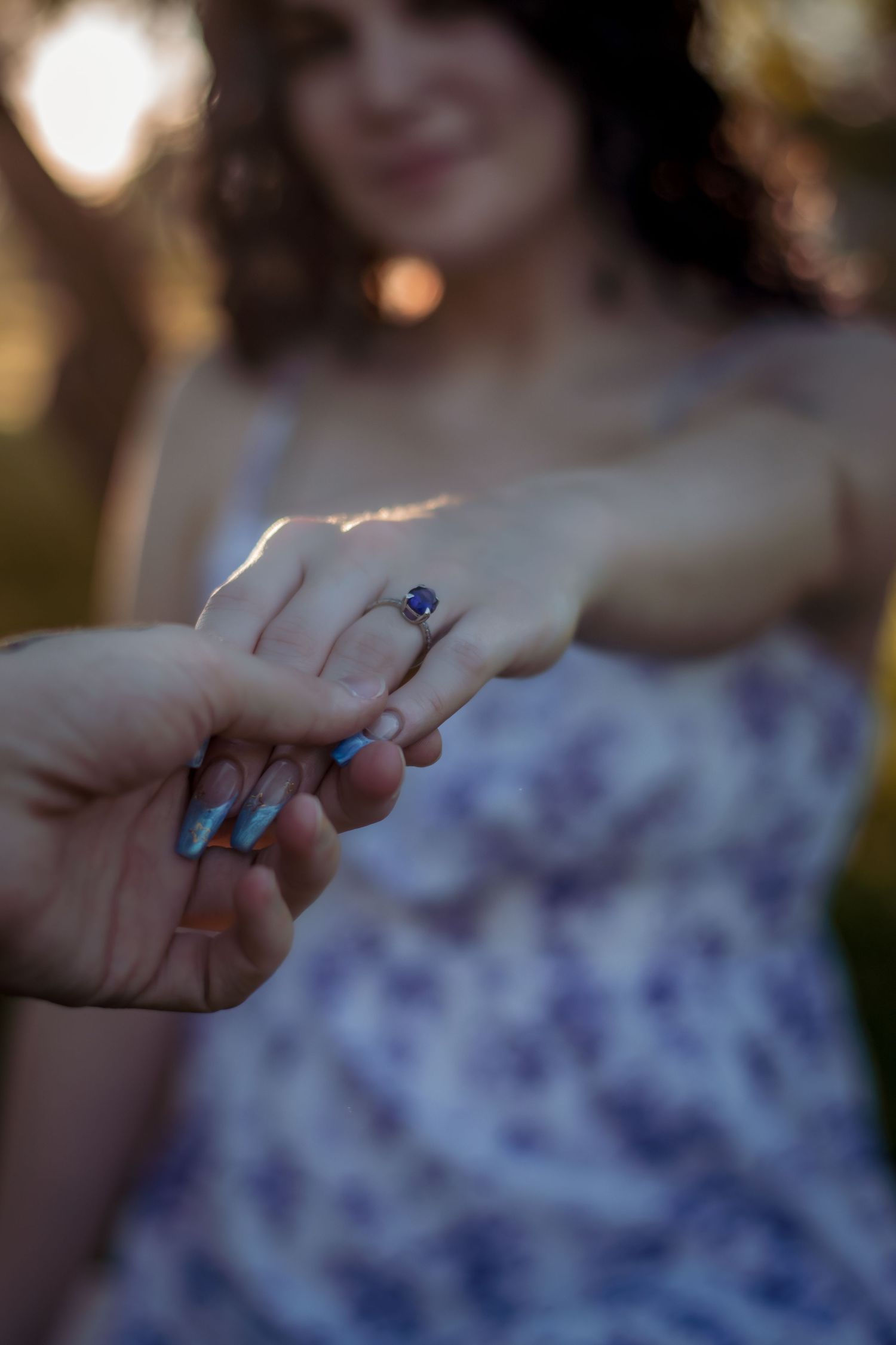 Close-up shots of hands displaying engagement and wedding rings with blue nail polish.