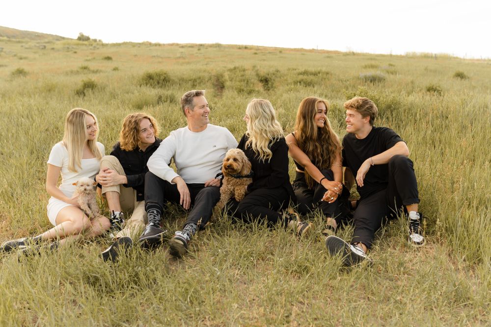 Casual group sitting together on grassy hillside in casual black and white outfits.