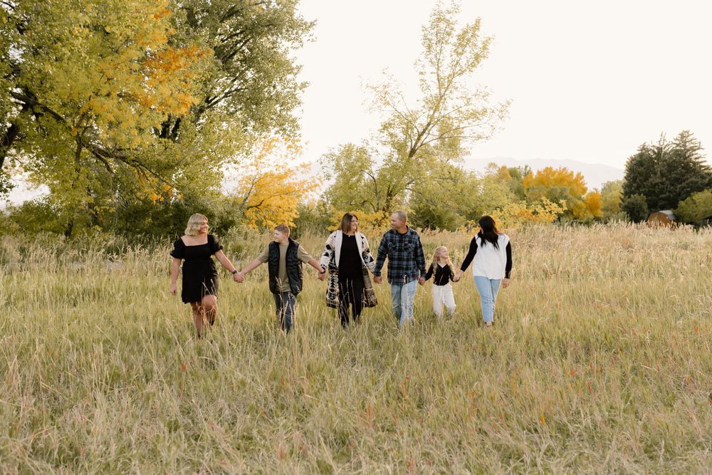 Group walking together through tall grass field during golden hour autumn sunset.
