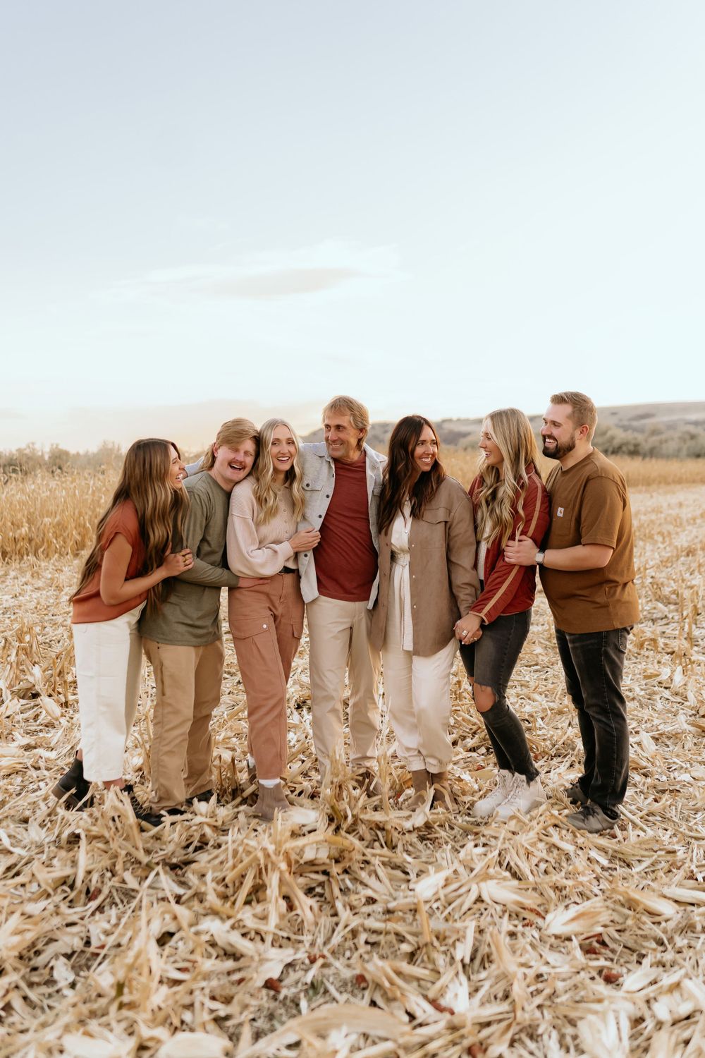 Friends gathered in a golden field at sunset wearing coordinated fall-colored clothing.
