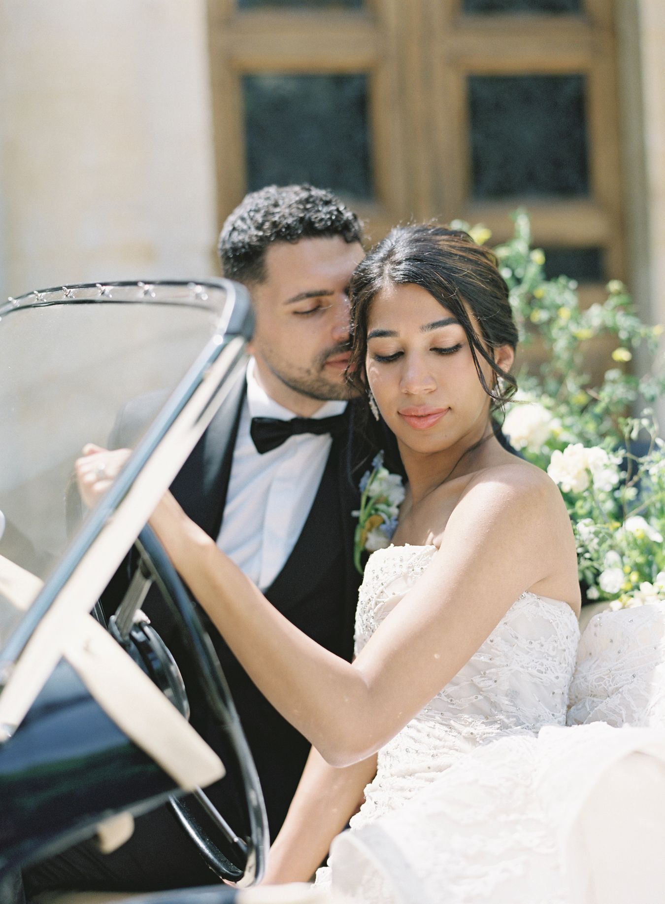 Romantic moment in vintage convertible car decorated with delicate floral arrangements.