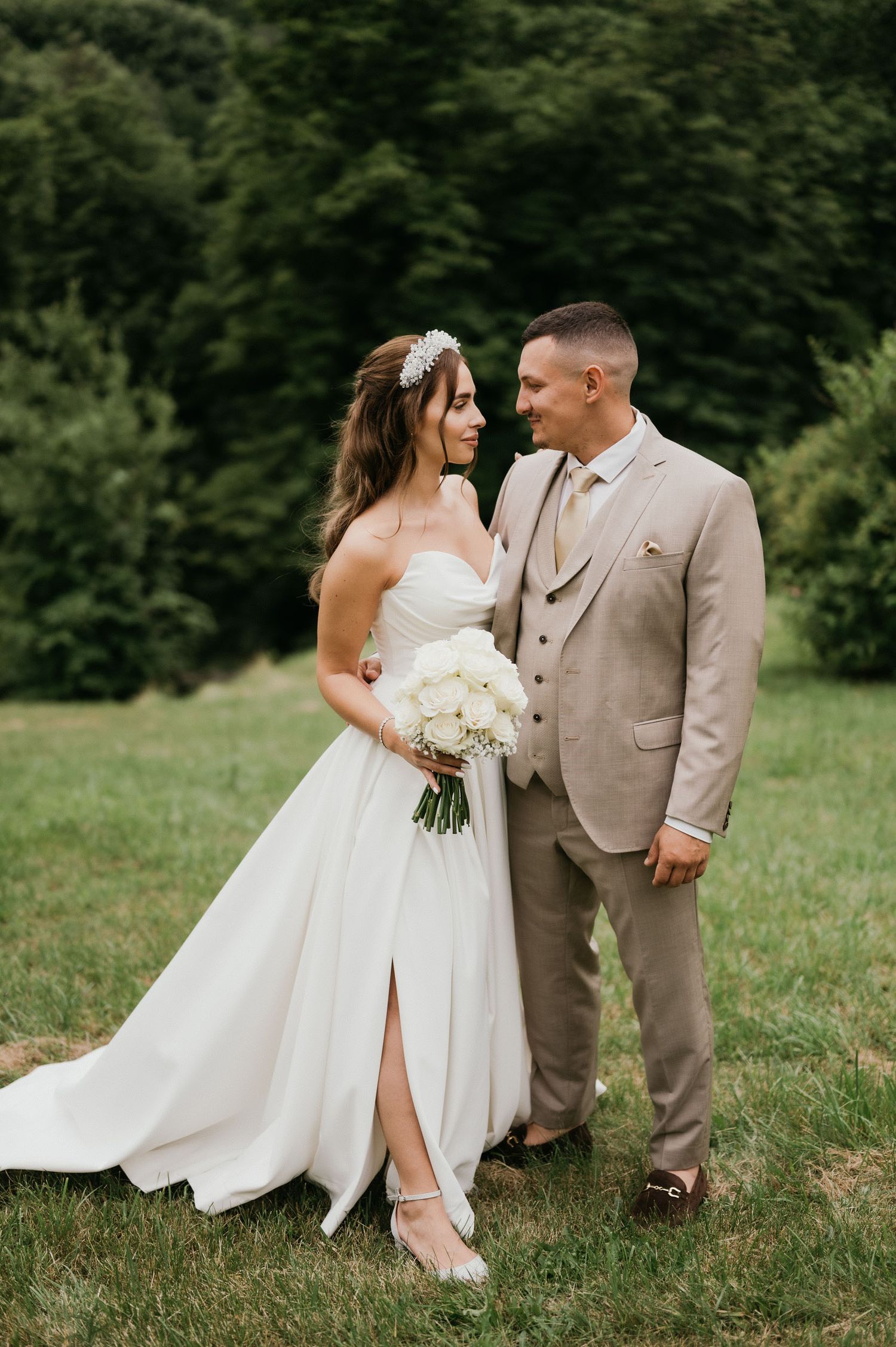 A couple stands together on their wedding day in a scenic mountain setting.