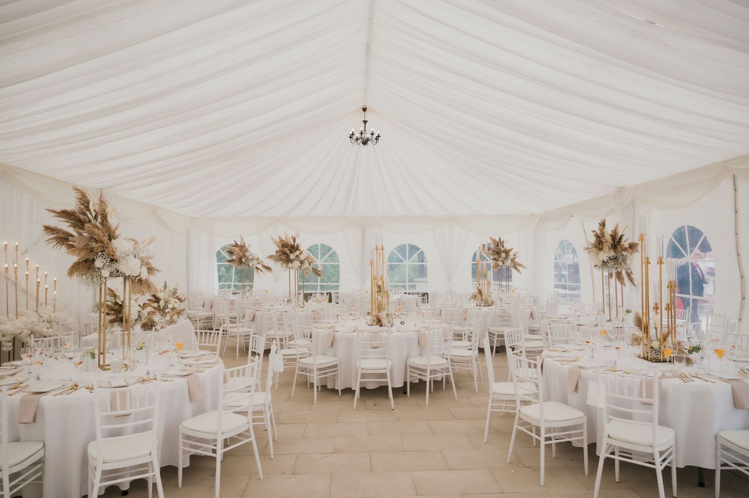 A white wedding tent interior decorated with dried floral arrangements and elegant table settings.