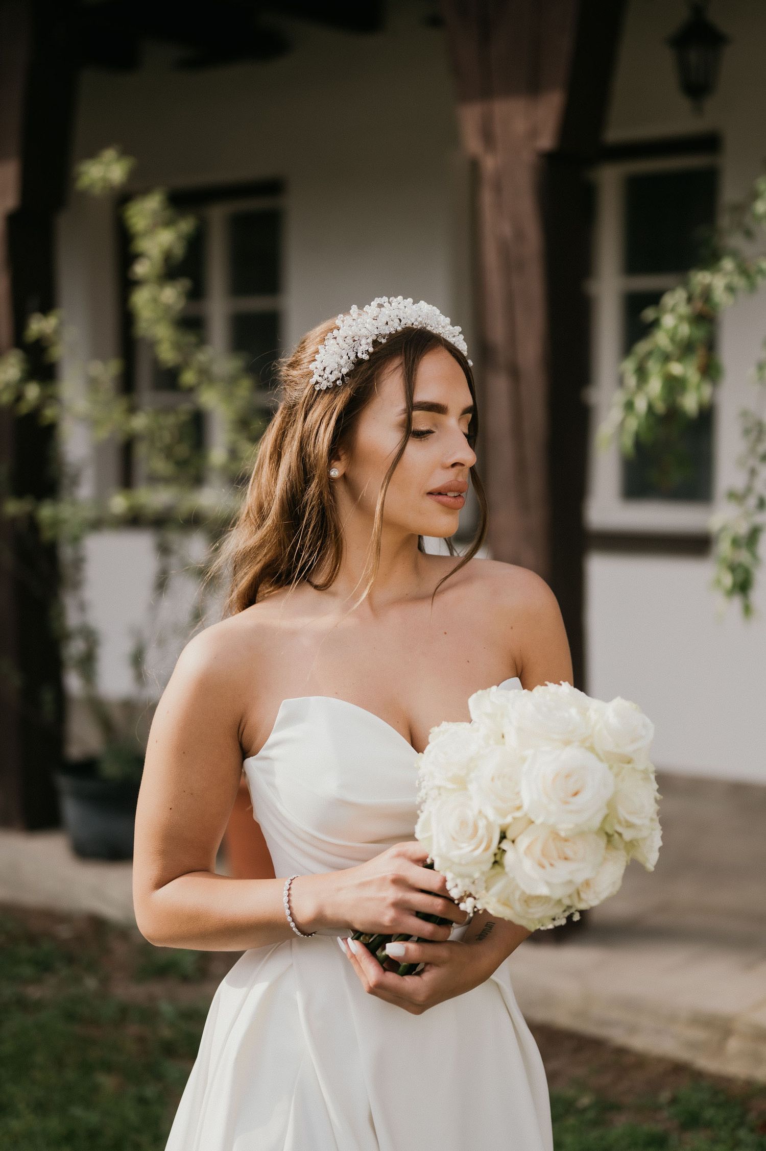 A candid bridal portrait shows a profile view with white roses against rustic architecture.