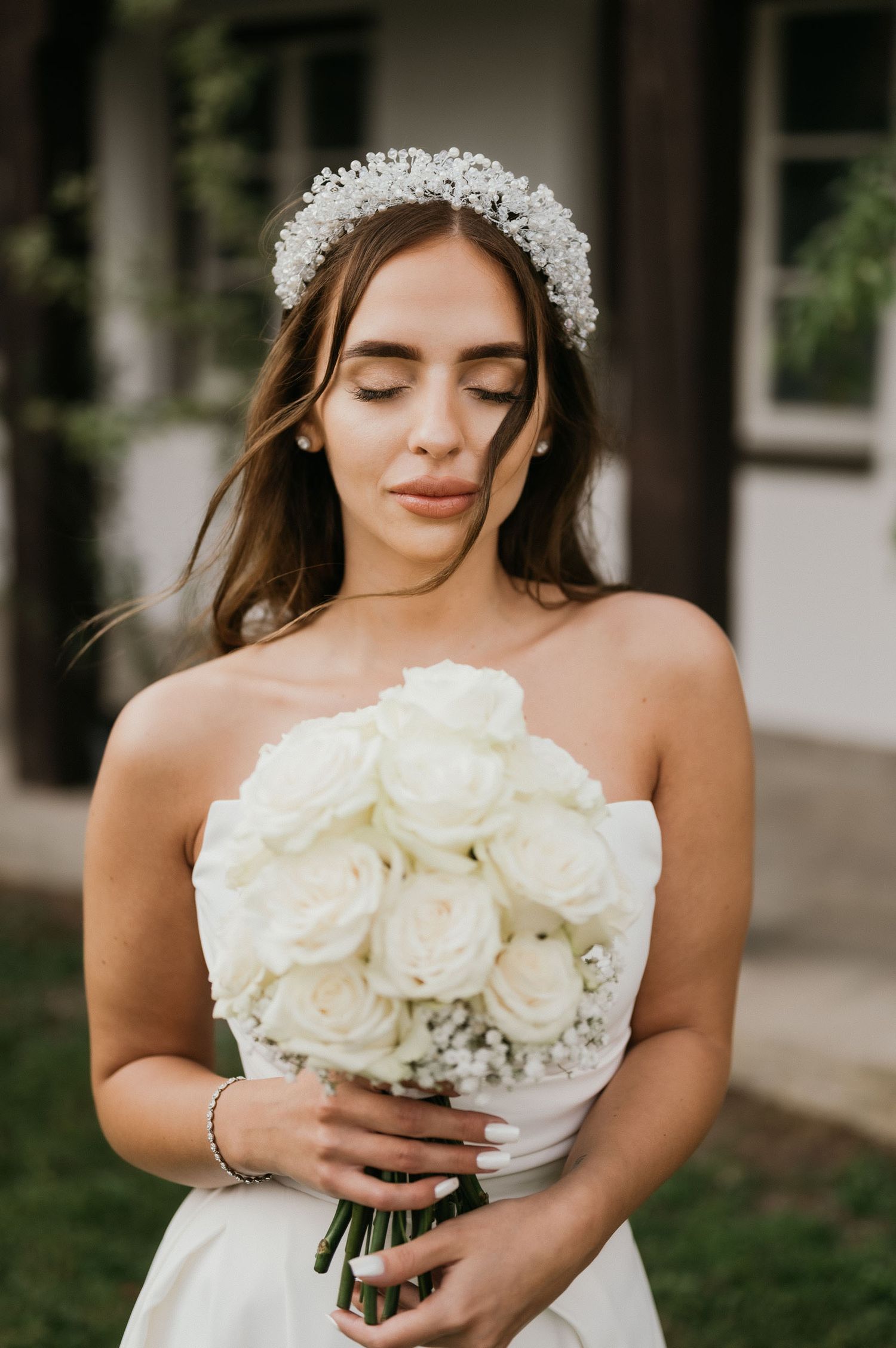 Dreamy bridal portrait featuring white strapless gown, crystal crown and classic white rose bouquet.