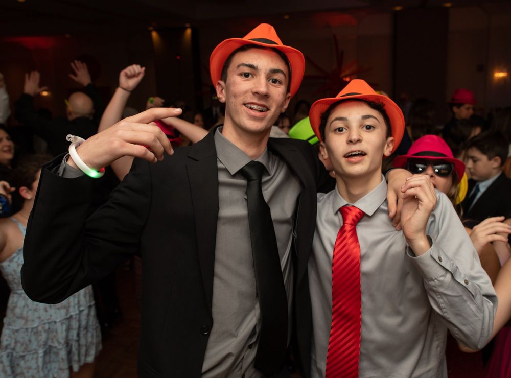 Party guests wearing fedora hats posing together at indoor celebration.
