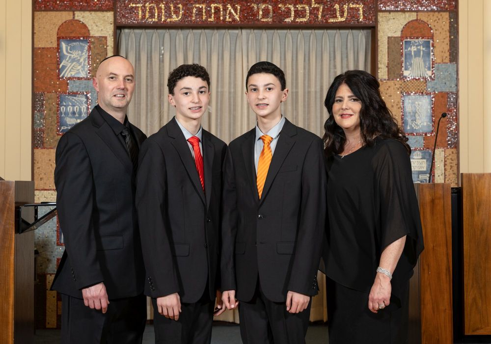 A family portrait taken in front of a synagogue altar with Hebrew writing.