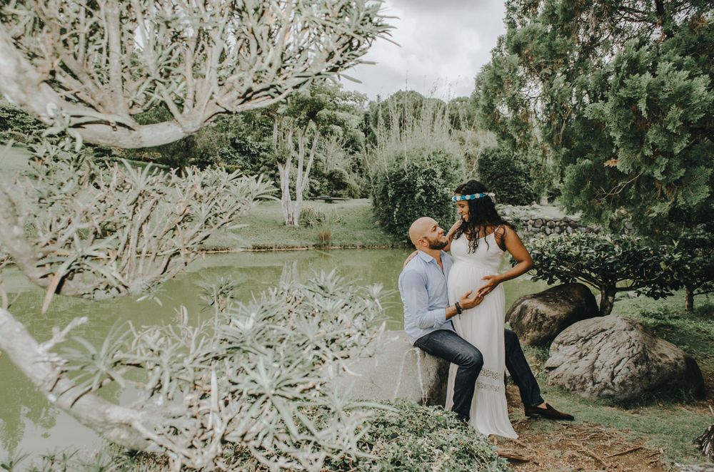 A couple poses together among white flowering branches in a natural outdoor setting.
