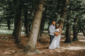 A romantic photoshoot in a wooded area with tall trees creating natural shade.