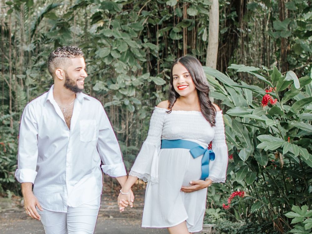 A couple shares an intimate moment in a lush garden setting with red flowers.