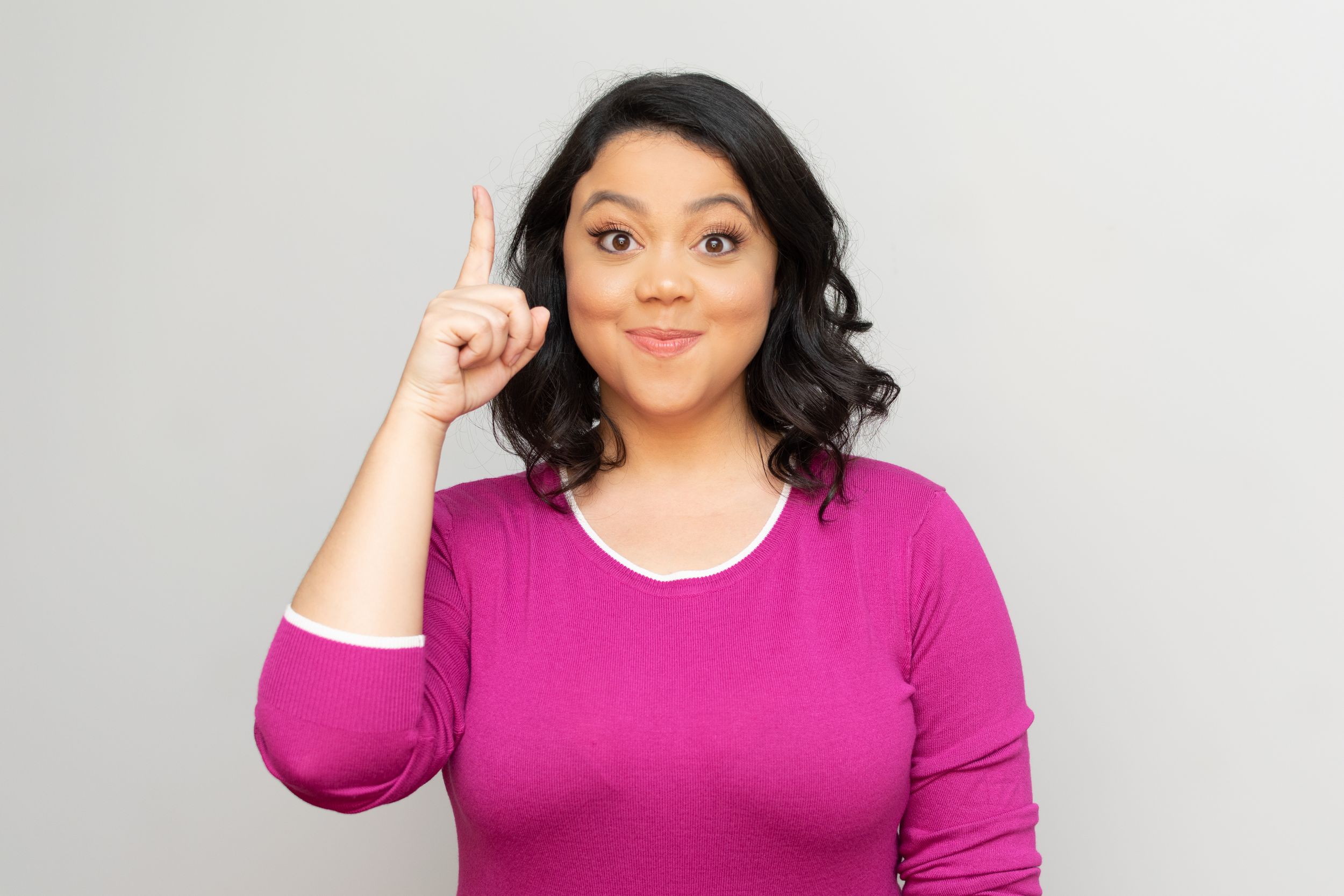 Person in magenta top making expressive gestures against white background.