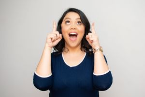 Person in navy top making animated gestures against white background.
