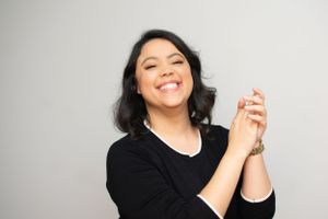 Woman in black attire showing joyful expressions and hand gestures.