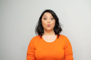 Someone in bright orange attire makes a playful surprised expression.