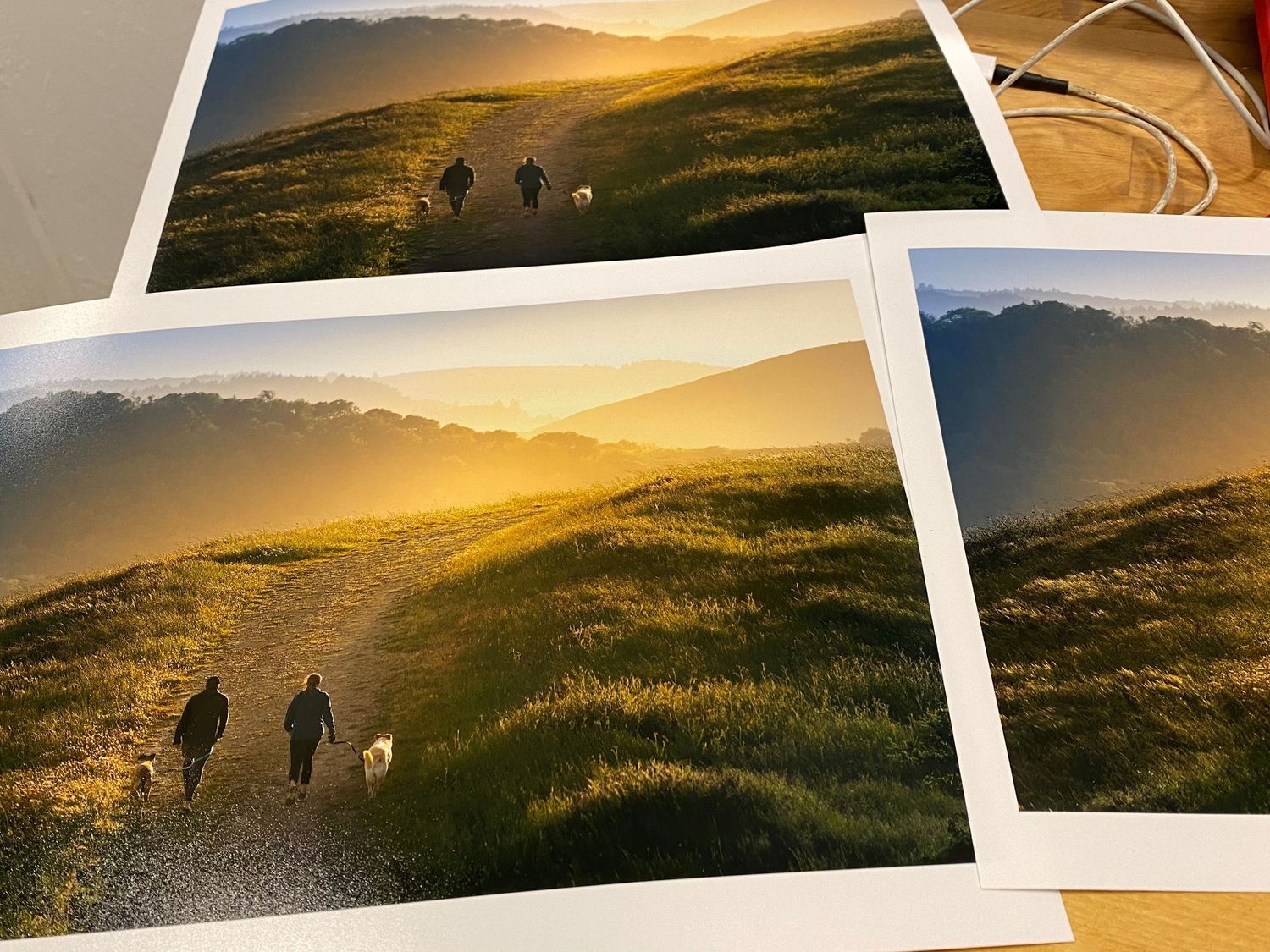 Printed photographs showing hiking trails at sunset across golden hillsides.