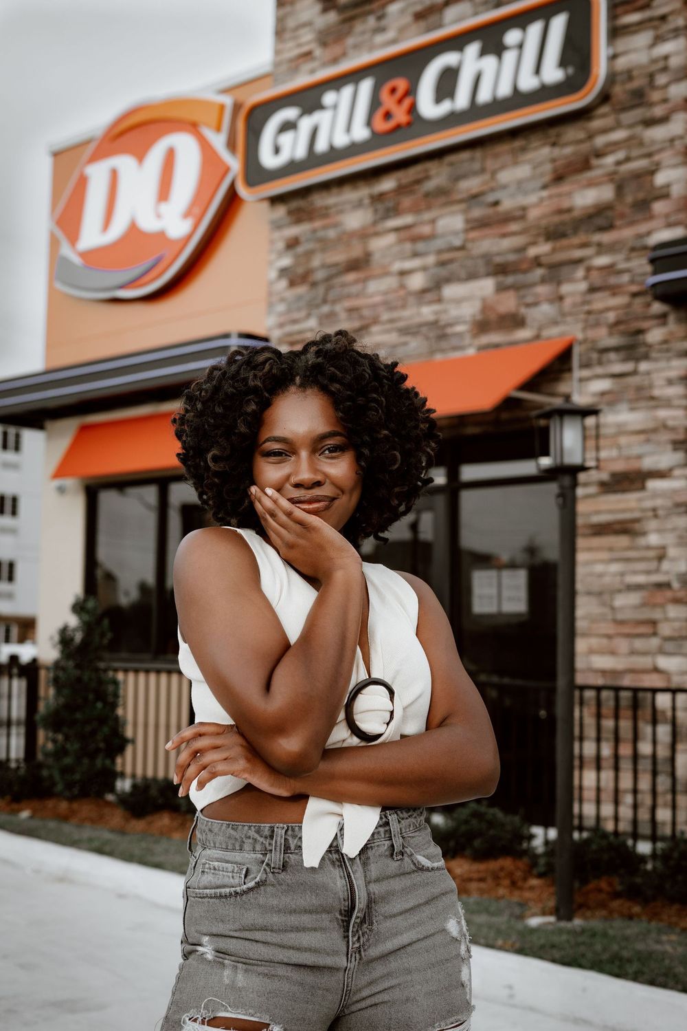 Casual summer portrait outside a Dairy Queen restaurant with stone facade and orange awning.