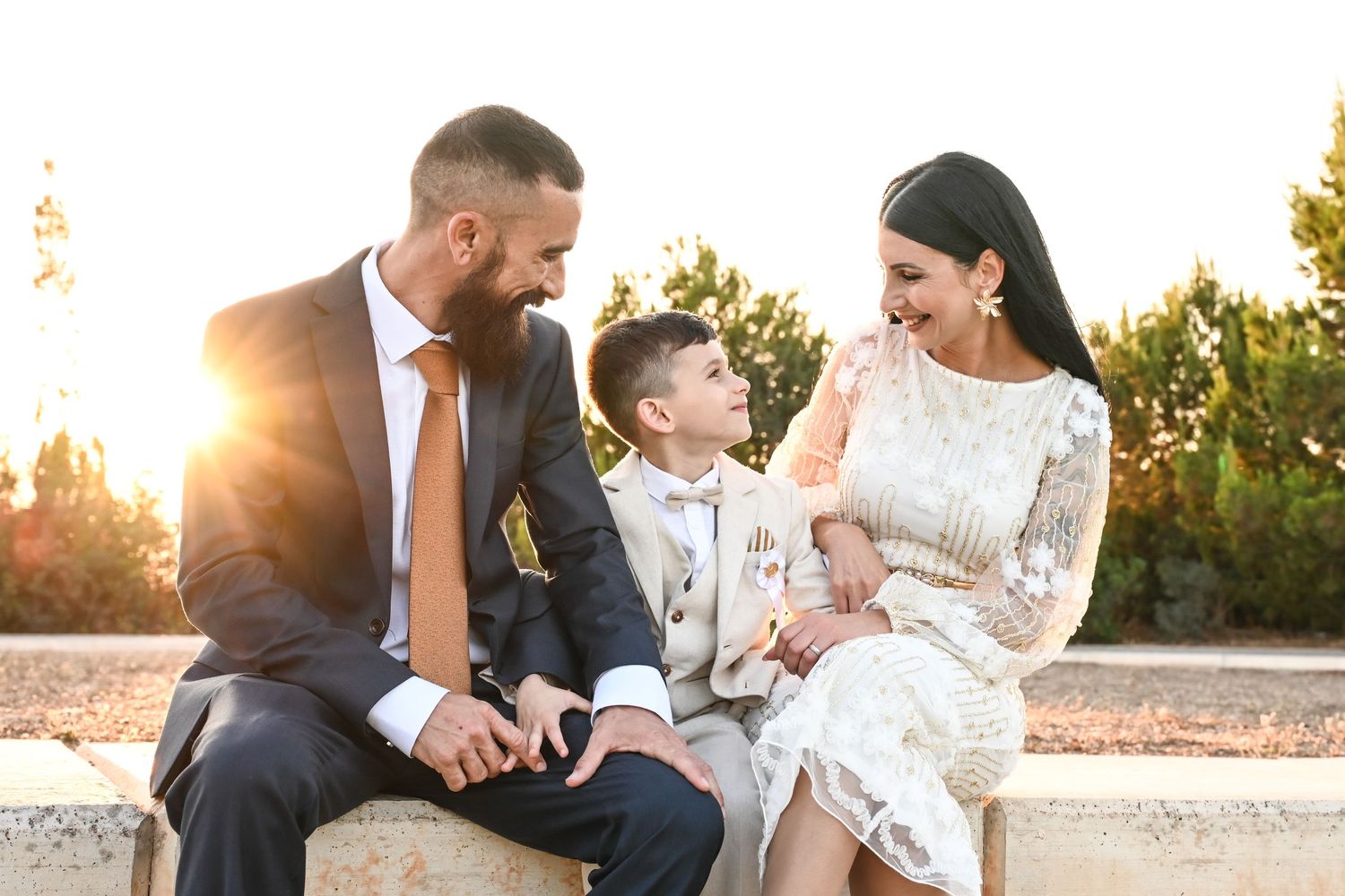 A family shares a tender sunset moment on an outdoor bench.