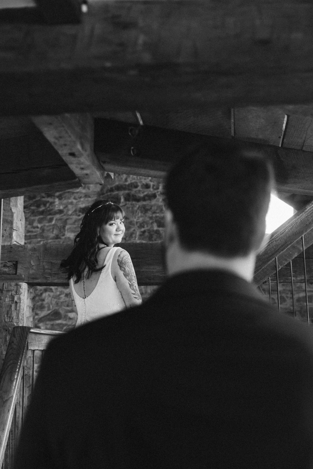 Dramatic black and white wedding photo capturing moment on rustic staircase.
