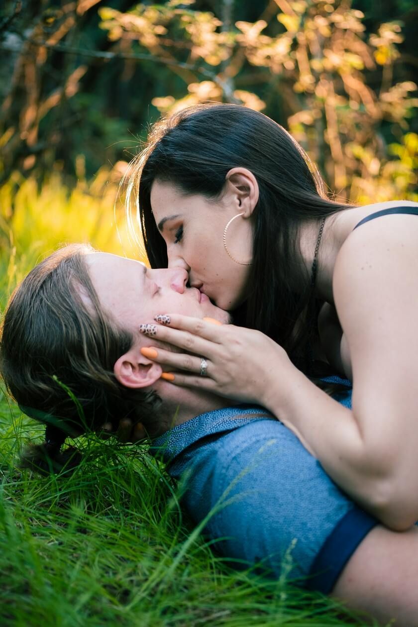 Engaged couple in grass with sunset backlight