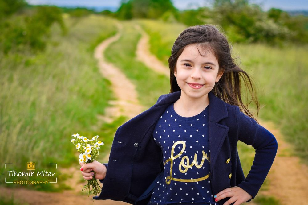Дете с синя рокля с букет на черен път