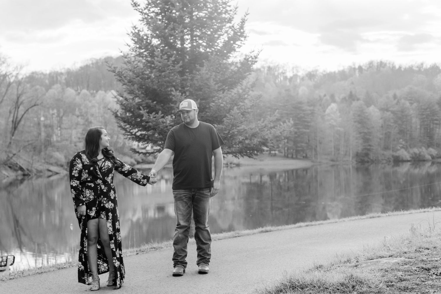 Black and white photo of a couple walking along a lakeside path.