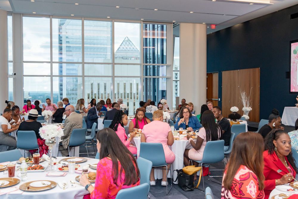 Large event space filled with round tables and guests gathering for a special occasion.