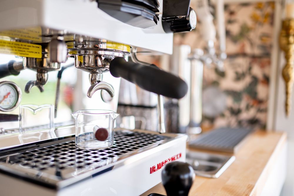 Professional espresso machine with chrome details and portafilter in a coffee shop setting.