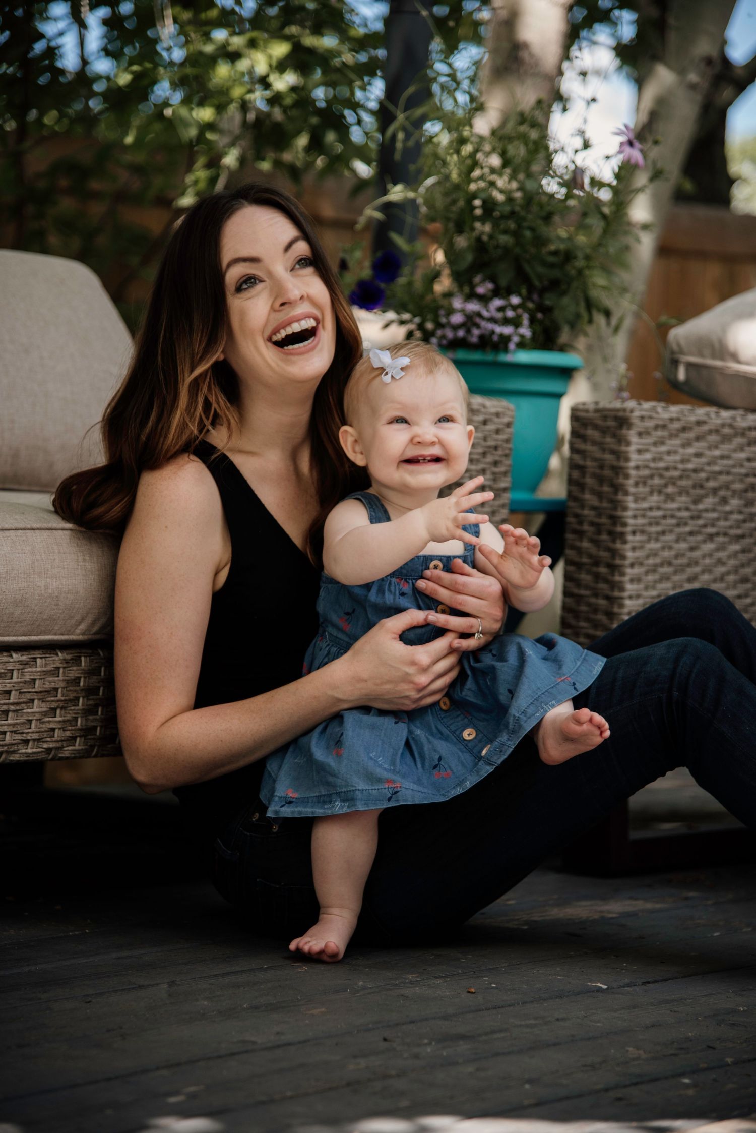 A joyful moment shared between parent and baby on outdoor patio furniture.