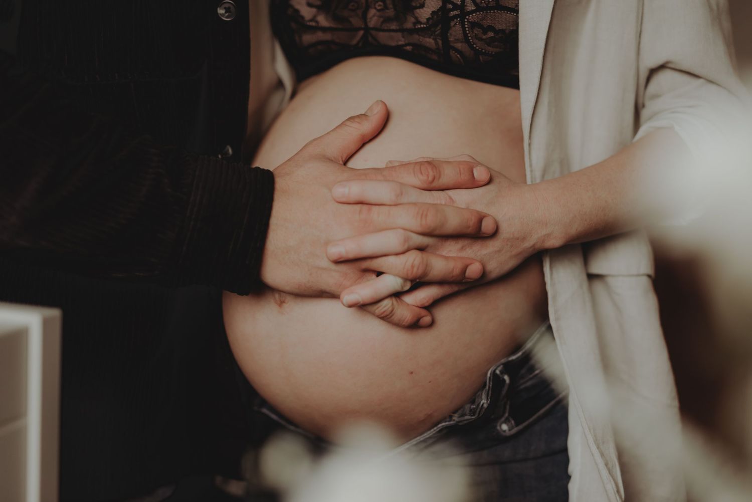 Hands gently resting on a pregnant belly in soft lighting, highlighting the maternal connection.