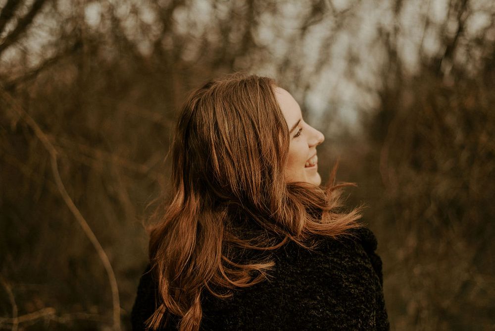 Artistic portrait in warm sepia tones showing flowing hair movement against natural backdrop.