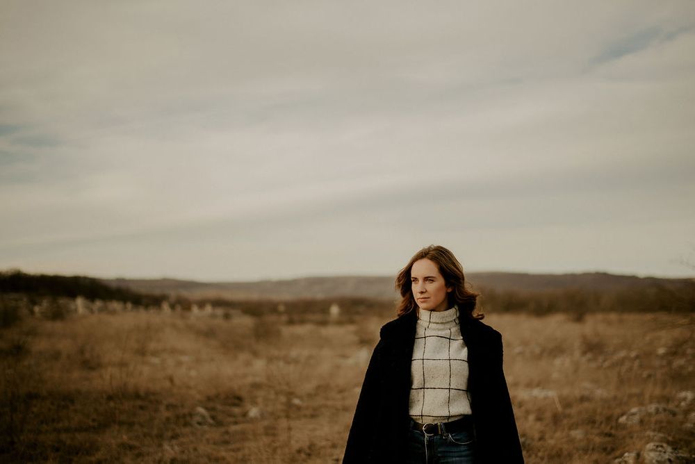 Atmospheric outdoor portraits set against rolling hills and cloudy skies.