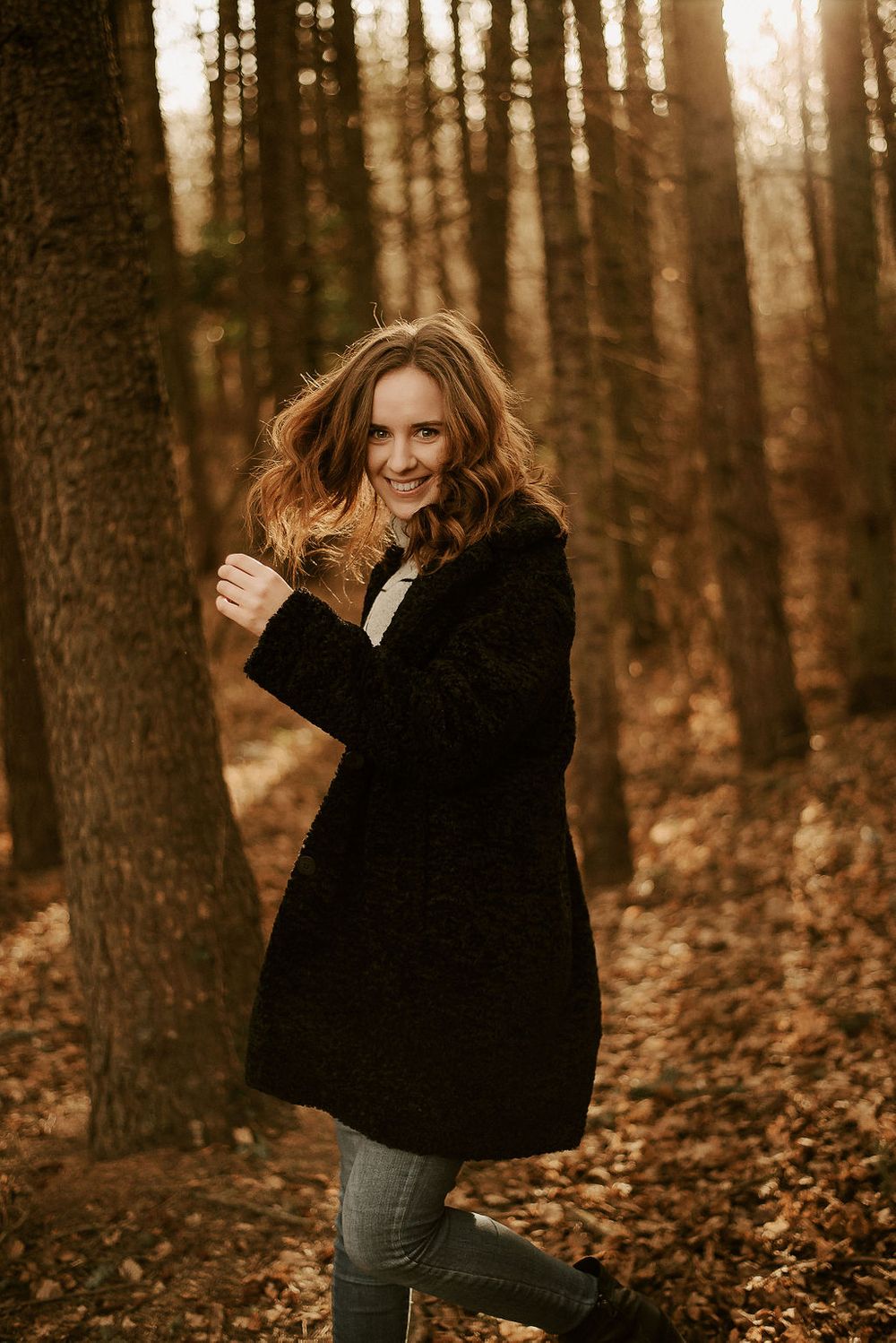 Playful autumn photoshoot with dynamic movement in wooded setting.