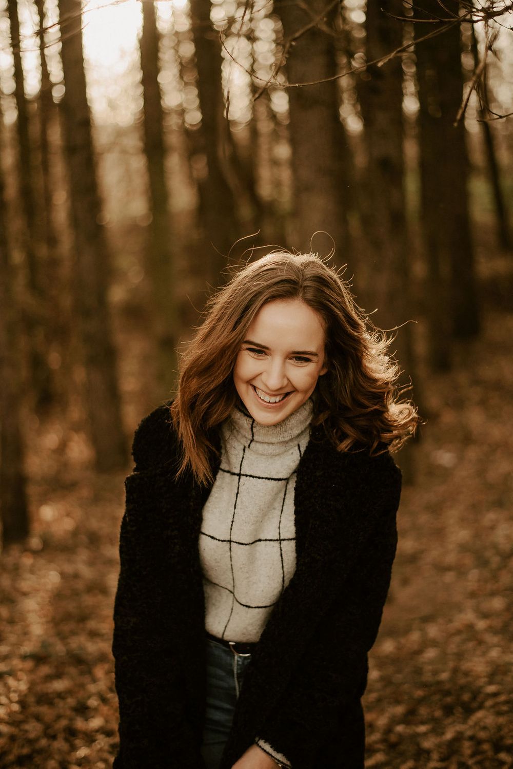 Candid laughing moment captured during forest photoshoot at sunset.