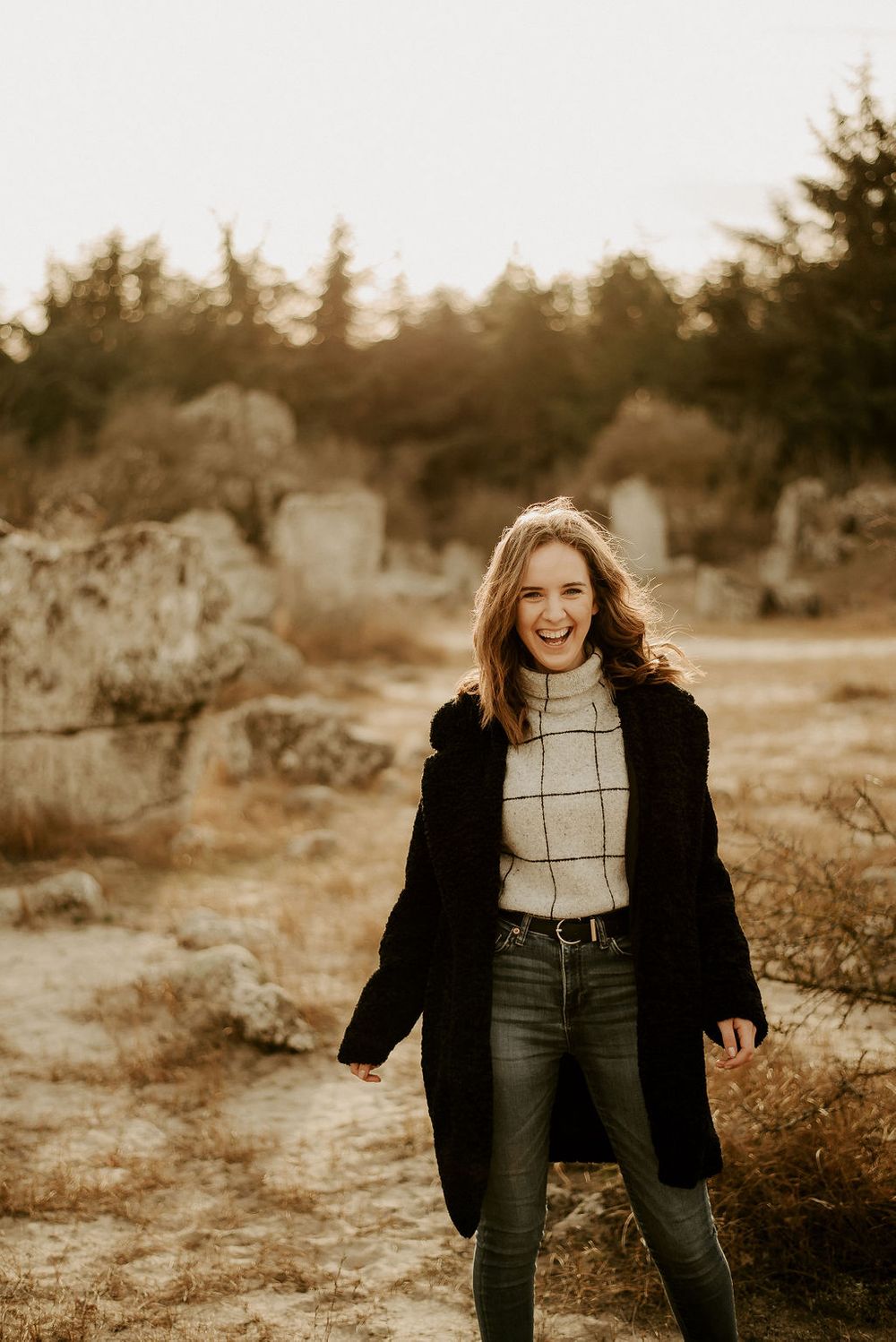 Candid outdoor fashion portrait with black coat and plaid sweater in sepia tones.
