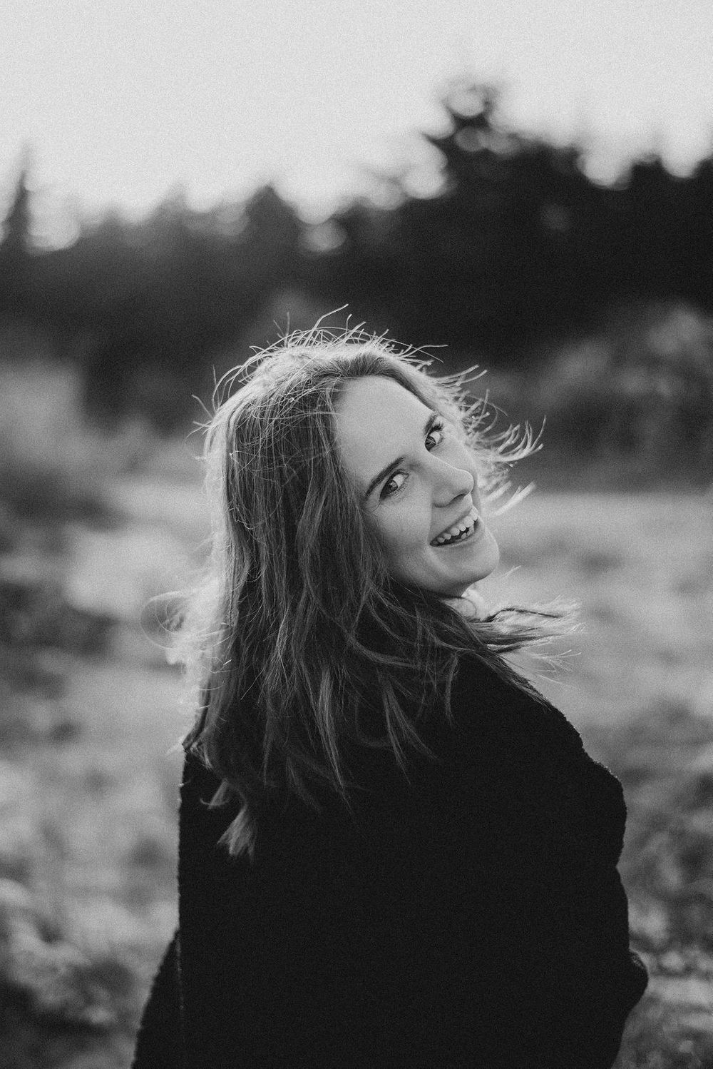 Dramatic black and white portraits with wind-swept hair against natural backdrop.