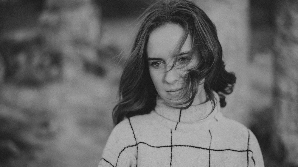 Artistic black and white close-up showing textured sweater and natural lighting.