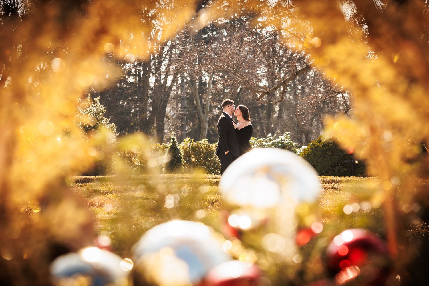 Couple embracing in a garden framed by golden autumn foliage and colorful ornaments.