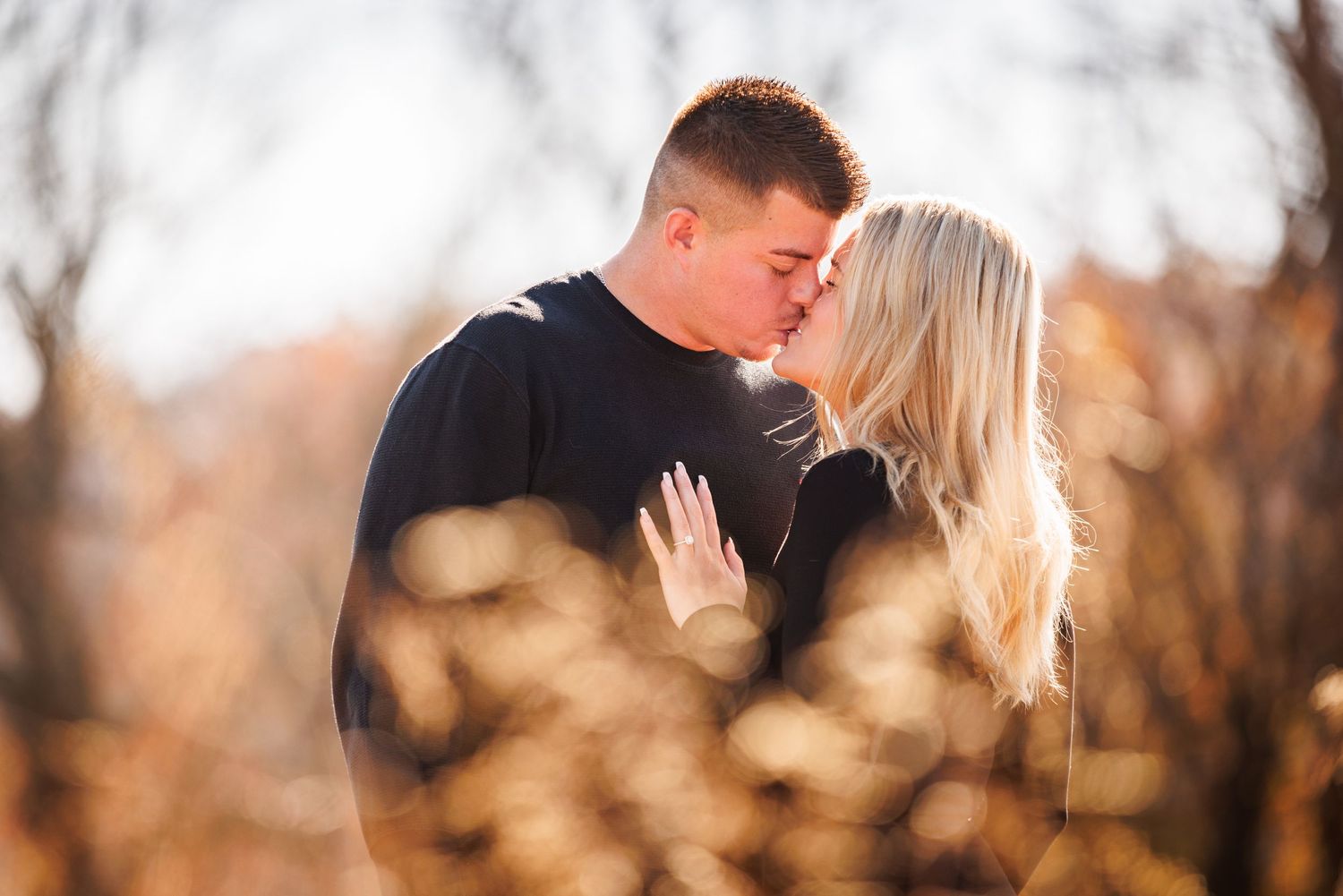 Couple sharing a tender almost-kiss surrounded by warm autumn bokeh foliage.