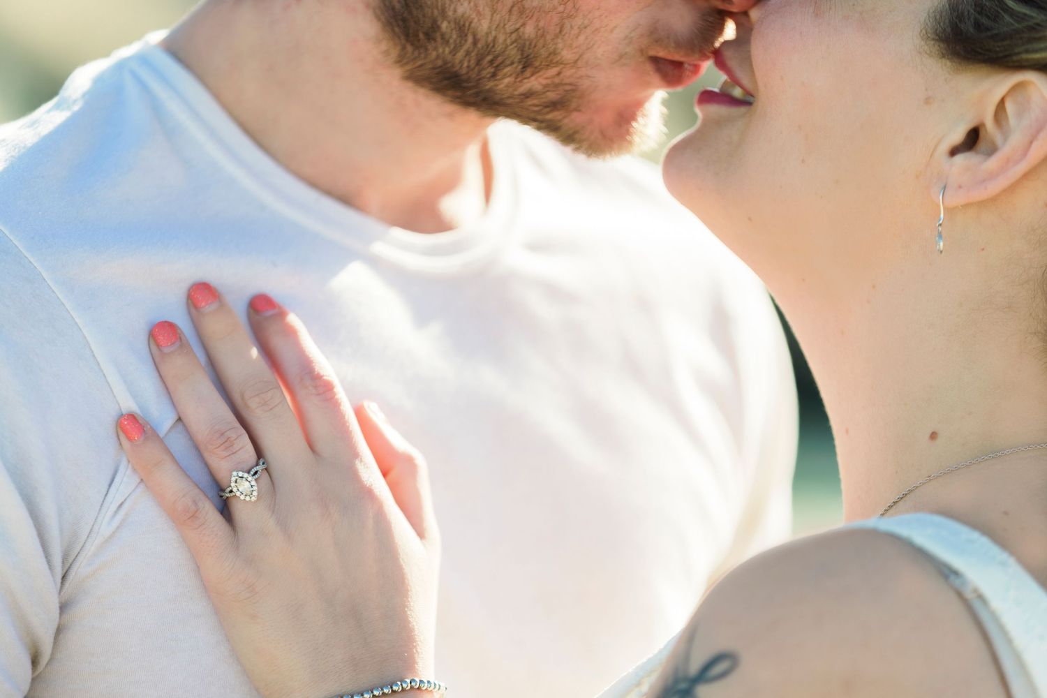 Close-up of couple kissing, woman's hand on man's chest showing engagement ring and bracelet.