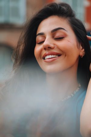 Close-up portrait showing joyful expression with closed eyes and natural makeup.